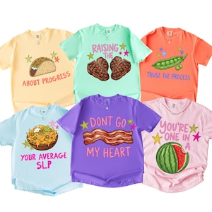 May include: Six short-sleeve t-shirts in pastel colors featuring food graphics and text. The shirts display a taco with 'About Progress', two steaks with 'Raising The', peas with 'Trust The Process', nachos with 'Your Average SLP', bacon with 'Dont Go My Heart', and a watermelon with 'You're One In A'.