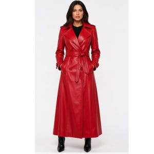 May include: A long, double-breasted red leather trench coat featuring a wide notched collar, shoulder epaulets, and long sleeves with buckled cuffs. The coat includes a matching tie belt at the waist, two rows of buttons, and a full-length skirt.