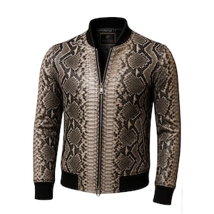 Könnte beinhalten: Eine Bomberjacke mit strukturiertem Schlangenledermuster in Beige-, Braun- und Schwarztönen. Die Jacke verfügt über einen schwarzen Rippstrickkragen, Rippbündchen an Ärmeln und Saum, einen durchgehenden Frontreißverschluss sowie zwei Seitentaschen.
