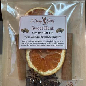 以下が含まれることがあります： 「Sweet Heat」のシマーポットキットが入った透明なビニール袋。 キットには、乾燥オレンジスライス、シナモンスティック、八角、ペッパーコーン、クローブ、赤唐辛子フレークが含まれています。 ラベルには「2 Spicy Girlz」と書かれています。