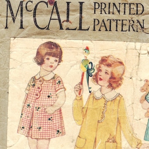May include: Vintage McCall's Printed Pattern featuring two young girls wearing dresses. The girl on the left is wearing a plaid dress with a white collar and short sleeves. The girl on the right is wearing a yellow dress with a white collar and long sleeves. She is holding a toy bird on a stick.