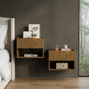 May include: Two wall-mounted wooden nightstands featuring a fluted, vertical-ribbed front panel design. Each unit includes an open storage shelf below the main surface, providing a floating appearance against the dark wall surface.