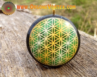 May include: A round, black pendant with a gold-colored loop at the top. The pendant features a green and gold flower of life design.