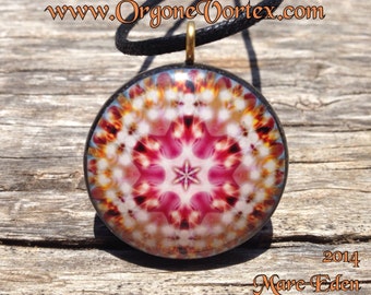 May include: A round, colorful pendant with a mandala design in shades of pink, white, and orange. The pendant is hanging from a black cord.