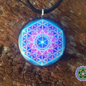 May include: A silver pendant with a black cord, featuring a blue, pink, and white geometric design inside a clear glass dome.