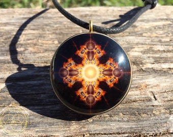 May include: A round pendant necklace with a black cord. The pendant features a gold-colored frame and a colorful, abstract design with shades of orange, yellow, and red.