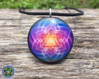 May include: A round pendant necklace with a black cord. The pendant features a colorful mandala design with a meditating figure in the center. The mandala is made of pink, purple, blue, and orange colors.