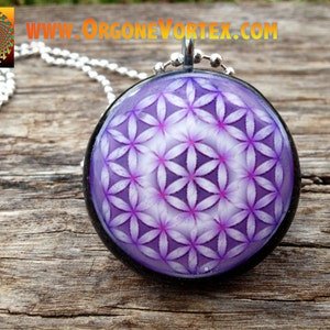 May include: A silver chain necklace with a round pendant featuring a purple and white flower of life design. The pendant has a black border.