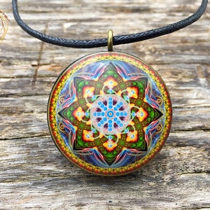 May include: A round pendant necklace with a colorful mandala design. The pendant is made of metal and has a black cord.