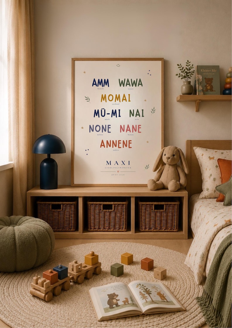 May include: A framed vertical poster with a white background featuring colorful text including AMM, WAWA, MOMAI, M&Uuml;-MI, NAI, NONE, NANE, ANNENE, and MAXI, decorated with small stars and leaf illustrations, displayed on a wooden shelf unit.
