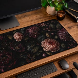 May include: A rectangular desk mat featuring a dark, moody floral pattern with large, detailed blooms in shades of deep burgundy, dusty pink, and muted purple, set against a black background with dark green foliage and intricate leaf textures.