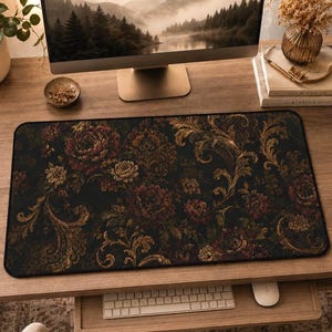 May include: A rectangular desk mat featuring a dark black background with a dense, intricate pattern of deep red and muted gold floral motifs and swirling acanthus leaf designs. The mat has a smooth surface and black stitched edges.