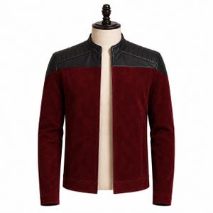Può includere: Giacca in camoscio bordeaux con inserti in pelle nera sulle spalle e sul colletto. La giacca ha un collo alto e una vestibilità classica e su misura. La giacca è esposta su un manichino.