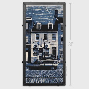 May include: Framed print of a street scene in shades of blue and white. The image features a vintage truck parked on a cobblestone street in front of a building. The print is 31 inches in height.