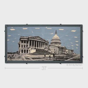 May include: Framed artwork featuring a black and white illustration of the U.S. Capitol Building and the Library of Congress against a light blue background. The frame is dark gray and the artwork measures 31 inches in width.