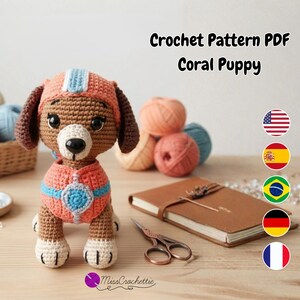 May include: A crocheted puppy toy with brown fur, a cream-colored muzzle, and a coral-colored outfit featuring light blue accents. The text 'Crochet Pattern PDF Coral Puppy' is visible at the top, and the logo 'MissCrochettie' is at the bottom.