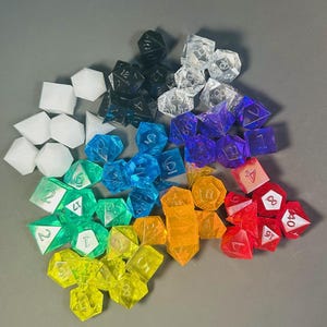 May include: A large collection of multi-sided polyhedral dice in a spectrum of colors including red, orange, yellow, green, blue, purple, black, white, and clear. Each die features engraved numbers, with various shapes like cubes, pyramids, and dodecahedrons.