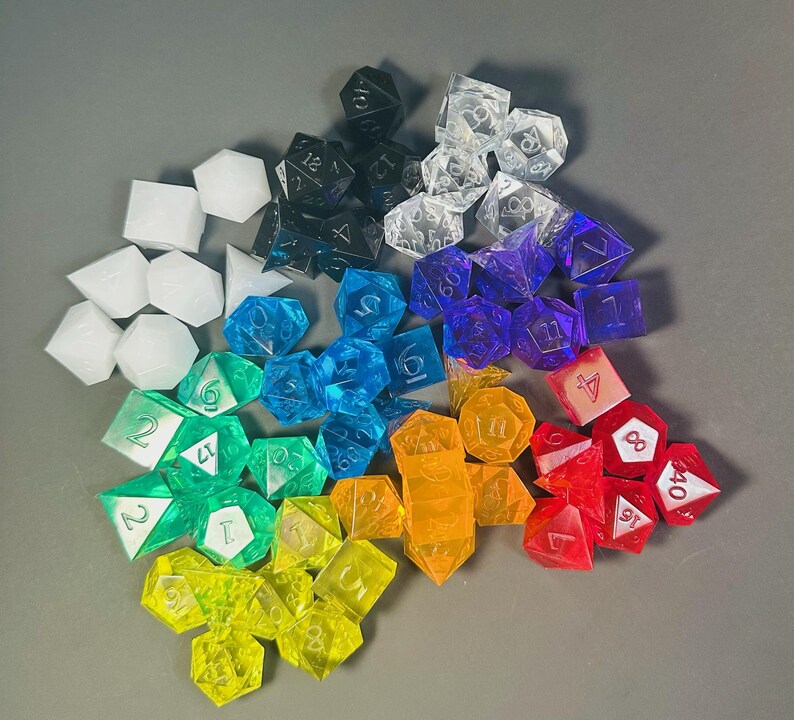 May include: A large collection of multi-sided polyhedral dice in a spectrum of colors including red, orange, yellow, green, blue, purple, black, white, and clear. Each die features engraved numbers, with various shapes like cubes, pyramids, and dodecahedrons.