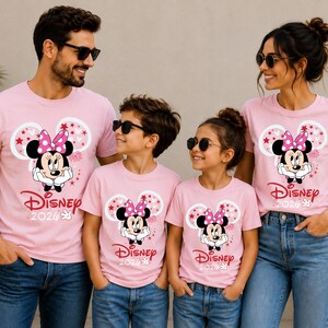 May include: Pink t-shirts featuring a Minnie Mouse graphic, worn by a family of four. The design includes Minnie's face, a pink bow, and the word "Disney" with the year "2020" printed below. The family is wearing sunglasses and blue jeans.