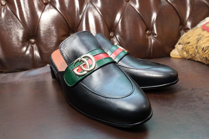Front view of luxury black leather clogs featuring a gold-tone buckle.