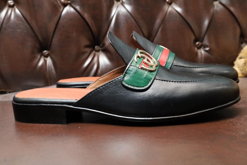 High-quality black leather loafers with a green and red webbed strap.