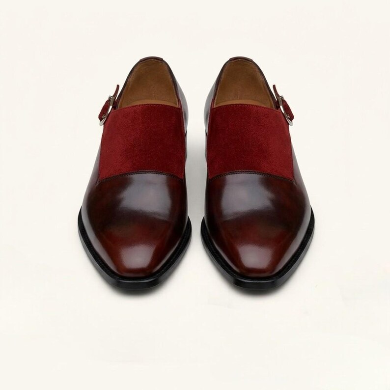 Handcrafted mens dress loafers in dark cherry leather resting on a clean cream background.
