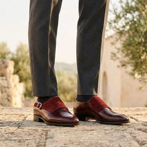 Close up of polished wine red leather and soft crimson suede on custom monk strap footwear.