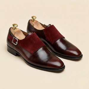 Close up of polished wine red leather and soft crimson suede on custom monk strap footwear.