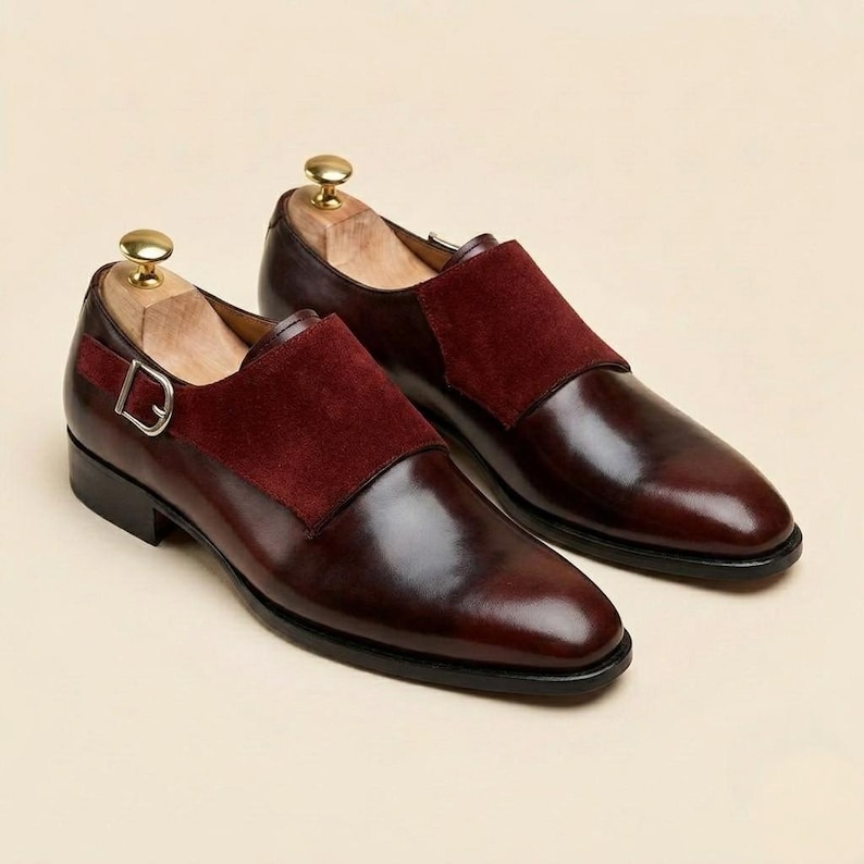 Close up of polished wine red leather and soft crimson suede on custom monk strap footwear.