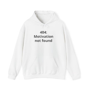Op de afbeelding: Witte hoodie met een voorzak en trekkoord. De voorkant heeft de zwarte tekst "404: Motivation not found". Een casual, comfortabel kledingstuk voor dagelijks gebruik.