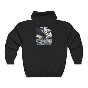 May include: A black zip-up hoodie featuring a graphic on the back of a bald eagle flying over a mountain range and water. The eagle has an arrow through its wing. Below the graphic, the text reads FLAWED BUT FORGIVEN in white capital letters.