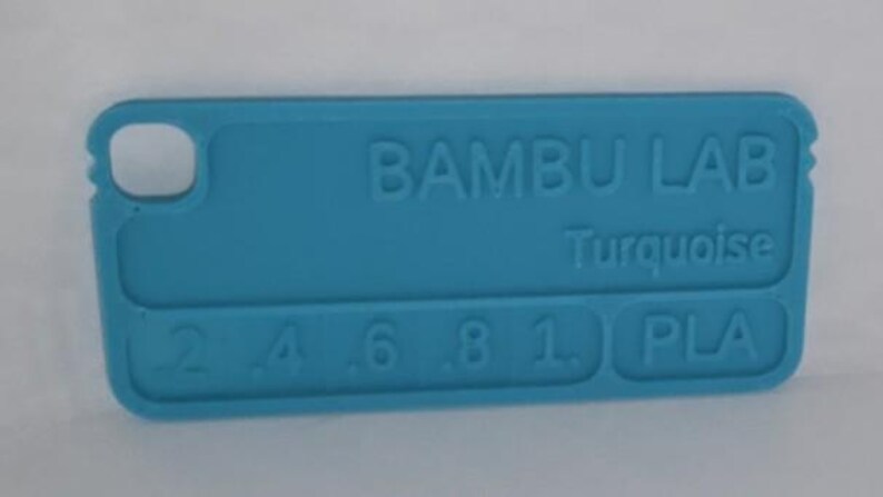 K&ouml;nnte beinhalten: Ein t&uuml;rkisfarbenes Kunststoff-Farbmuster von Bambu Lab. Das Muster tr&auml;gt den Text "BAMBU LAB Turquoise" und die Zahlen 2, 4, 6, 8, 1 und PLA. Es hat ein Loch auf der linken Seite.