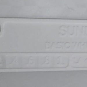 K&ouml;nnte beinhalten: Ein wei&szlig;es rechteckiges Objekt mit abgerundeten Ecken, mit dem gepr&auml;gten Text "SUNILU BASIC WHITE". Darunter befinden sich Zahlen und Symbole. Das Objekt hat ein kleines, erhabenes kreisf&ouml;rmiges Element.