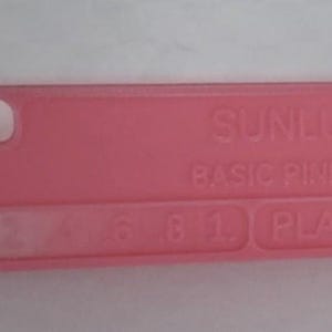 K&ouml;nnte beinhalten: Ein rechteckiges, rosa Kunststoffobjekt mit abgerundeten Ecken. Der Text "SUNLU BASIC PINK" ist auf der Oberfl&auml;che aufgedruckt. Es hat ein Loch und mehrere kleine rechteckige Aussparungen. Es ist wahrscheinlich eine Handyh&uuml;lle.