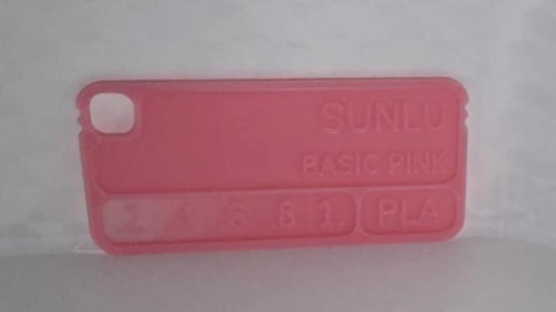 K&ouml;nnte beinhalten: Ein rechteckiges, rosa Kunststoffobjekt mit abgerundeten Ecken. Der Text "SUNLU BASIC PINK" ist auf der Oberfl&auml;che aufgedruckt. Es hat ein Loch und mehrere kleine rechteckige Aussparungen. Es ist wahrscheinlich eine Handyh&uuml;lle.