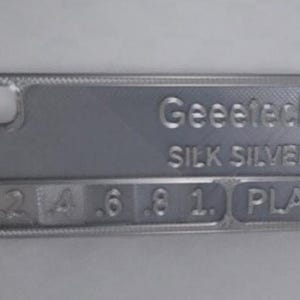 K&ouml;nnte beinhalten: Eine silberfarbene Handyh&uuml;lle mit dem Text "Geeetech SILK SILVER" und den Zahlen 2, 4, 6, 8, 1 und den Buchstaben PLA. Die H&uuml;lle hat eine strukturierte Oberfl&auml;che und einen Kameraausschnitt.