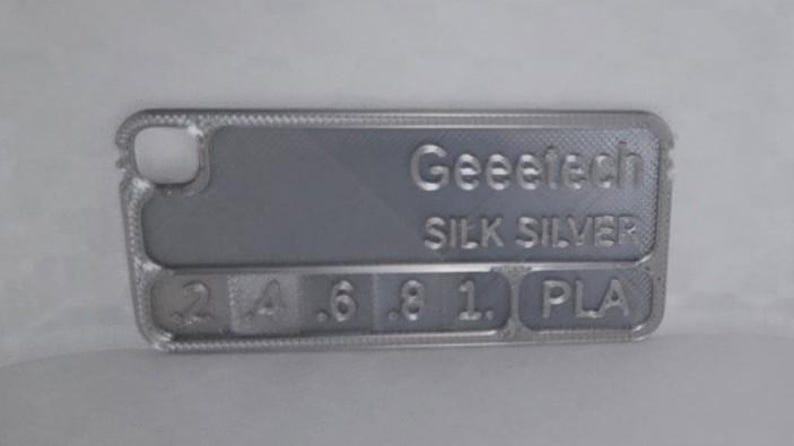 K&ouml;nnte beinhalten: Eine silberfarbene Handyh&uuml;lle mit dem Text "Geeetech SILK SILVER" und den Zahlen 2, 4, 6, 8, 1 und den Buchstaben PLA. Die H&uuml;lle hat eine strukturierte Oberfl&auml;che und einen Kameraausschnitt.