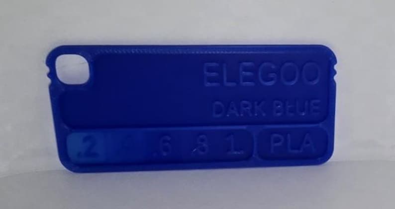 K&ouml;nnte beinhalten: Ein dunkelblaues ELEGOO PLA-Filament-Farbmuster. Das rechteckige Muster hat abgerundete Ecken und ein Loch an einem Ende. Der Text "ELEGOO DARK BLUE" und Zahlen sind auf der Oberfl&auml;che gepr&auml;gt.