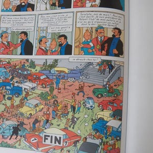 May include: A comic book page featuring Tintin characters in dialogue panels above a large, detailed illustration of a car rally scene. The scene depicts numerous vintage cars in various colors, people, and a finish line sign labeled FIN.