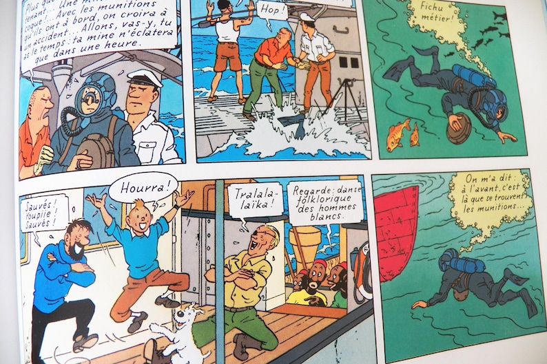 May include: A comic book page featuring multiple panels with illustrations of characters on a ship and underwater. The scenes depict a diver in a suit, people talking on a deck, a person jumping for joy, and a diver swimming near a red boat hull.
