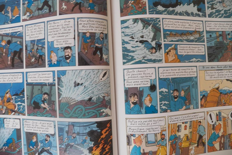 May include: A comic book page featuring multiple panels with illustrations of Tintin and Captain Haddock on a ship. The scenes depict characters in blue shirts reacting to a fire, using a fire hose, and navigating rough seas with speech bubbles.