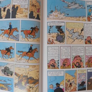 May include: A two-page spread from a Tintin comic book featuring multiple colorful panels. The illustrations depict desert scenes with characters riding horses, airplanes flying overhead, military vehicles, and figures in traditional headwear.