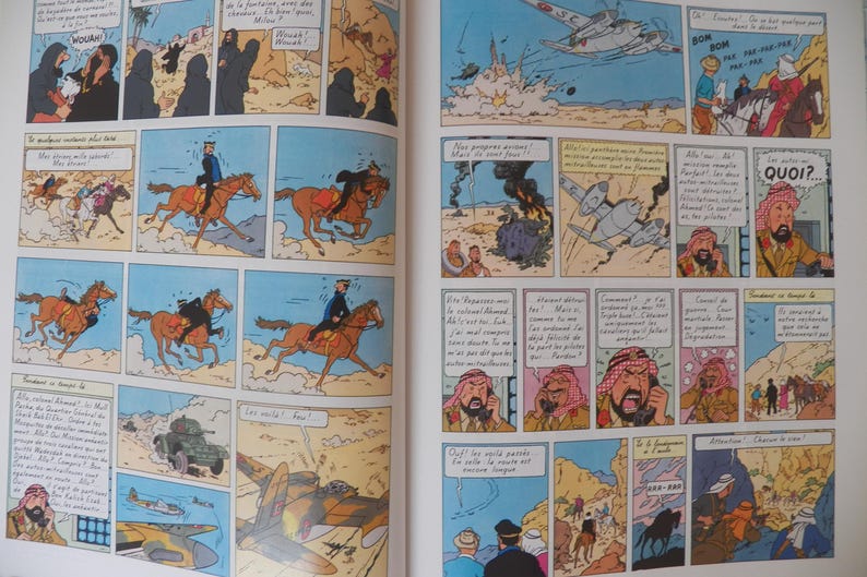 May include: A two-page spread from a Tintin comic book featuring multiple colorful panels. The illustrations depict desert scenes with characters riding horses, airplanes flying overhead, military vehicles, and figures in traditional headwear.