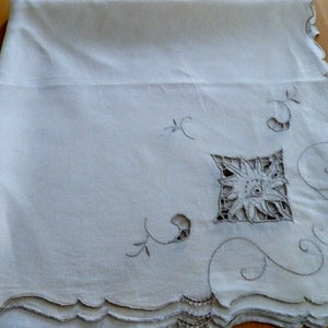 May include: White linen tablecloth with delicate embroidered floral designs and scalloped edges.