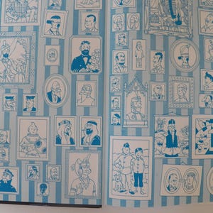May include: A light blue and white vertical striped wallpaper featuring a repeating pattern of various framed illustrations of characters and scenes in blue ink. The design includes numerous portraits, rectangular frames, and oval frames.