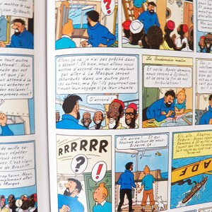 May include: A comic book page featuring multiple panels with illustrations of Tintin and Captain Haddock. The scenes depict characters on a ship, dialogue bubbles with French text, and a yellow airplane flying over a boat in the ocean.