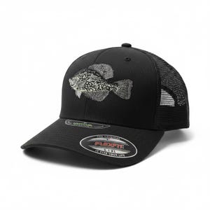 Può includere: Cappellino da baseball nero con retro in rete e visiera curva. Il cappellino presenta un design di pesce ricamato dettagliato in tonalità di grigio e bianco. Il logo Flexfit è visibile sul davanti.