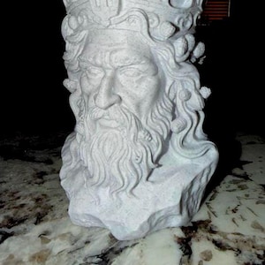 May include: A light gray, speckled planter shaped like the head of a bearded figure wearing a crown. The sculpture features detailed facial hair, flowing locks of hair, and small decorative elements integrated into the crown and hair design.