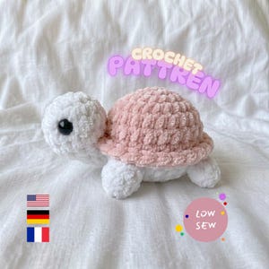 Könnte beinhalten: Ein gehäkeltes Plüsch-Schildkrötenspielzeug mit weißem Kopf, Gliedmaßen und Bauch sowie einem weichen rosa Panzer und großen schwarzen Sicherheitsaugen. Der Text CROCHET PATTREN ist lila und ein rosa Kreis enthält den Text LOW SEW.