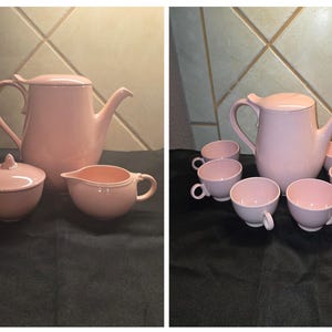 May include: A light pink ceramic tea set consisting of a teapot with a lid, a lidded sugar bowl, a creamer pitcher, and six matching tea cups. Each piece features a smooth, solid-colored finish with curved handles and a consistent design aesthetic.